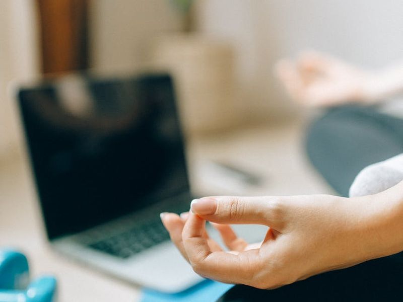 A yoga mat rolled out on a wooden floor in a sunlit room.